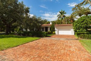 White brick home in suburban Floridian neighborhood on sunny day